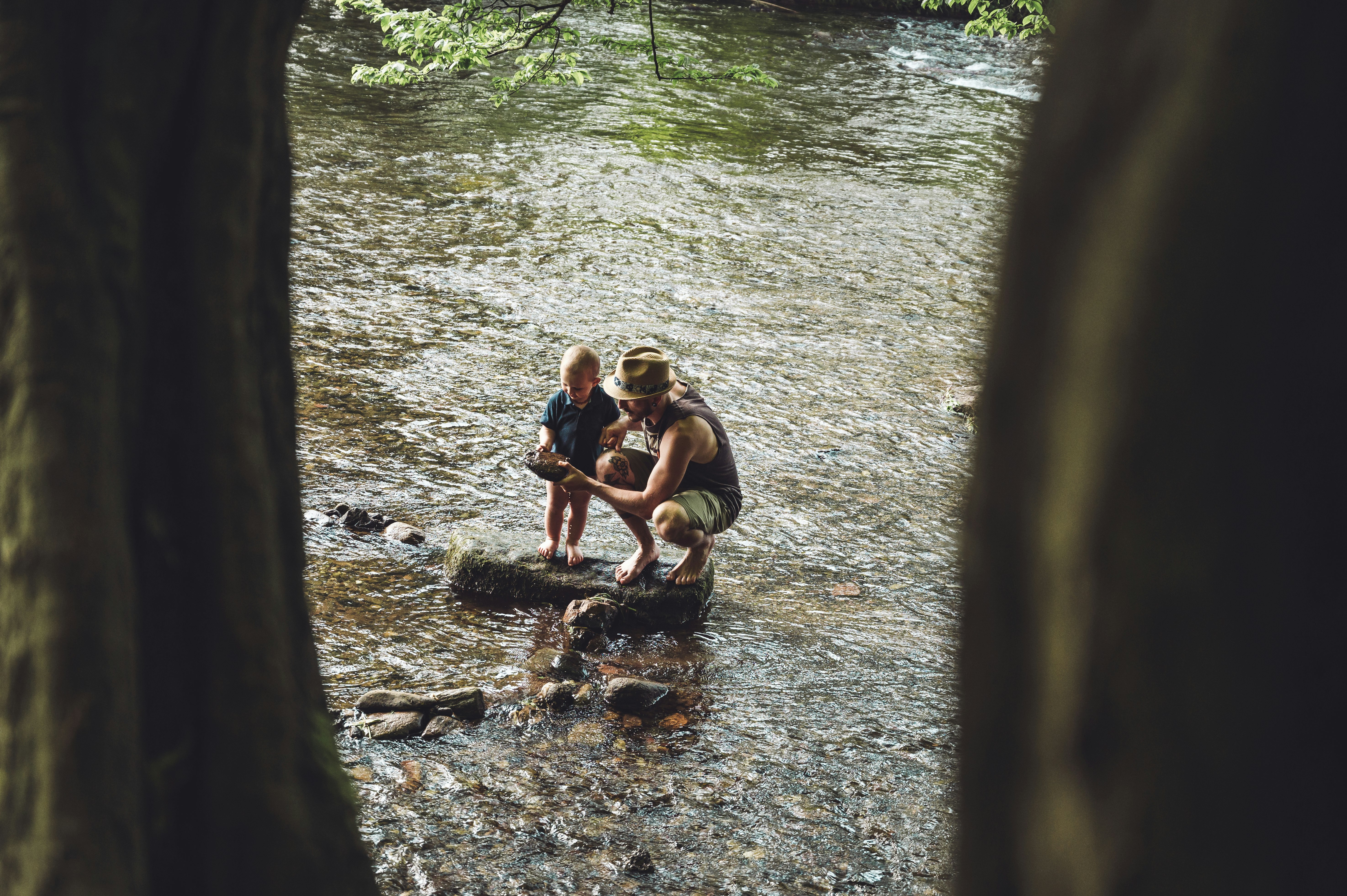 3 women sitting on rock in river during daytime